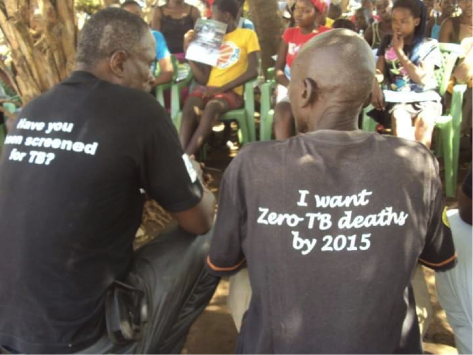 Two people with their backs to the camera, both wearing t-shirts that read 'I want zero TB death by 2015'