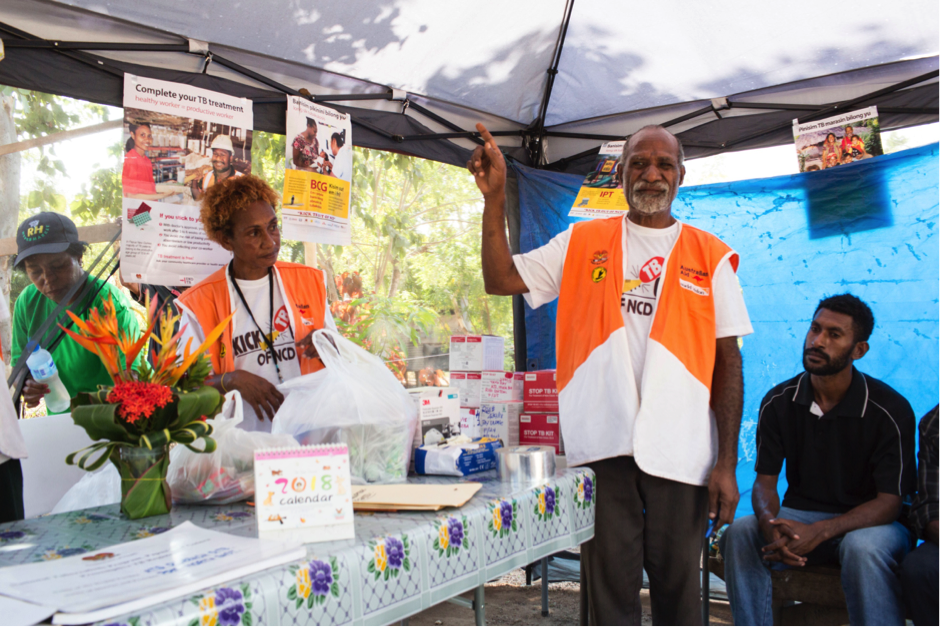 Volunteer health worker Rodney Kove speaks to people with TB about the side effects of their treatment at an outreach post outside his home in ATS settlement, Port Moresby